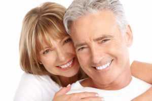 Happy couple smiling with perfect smiles from dentures and implant therapy in Port St. Lucie.